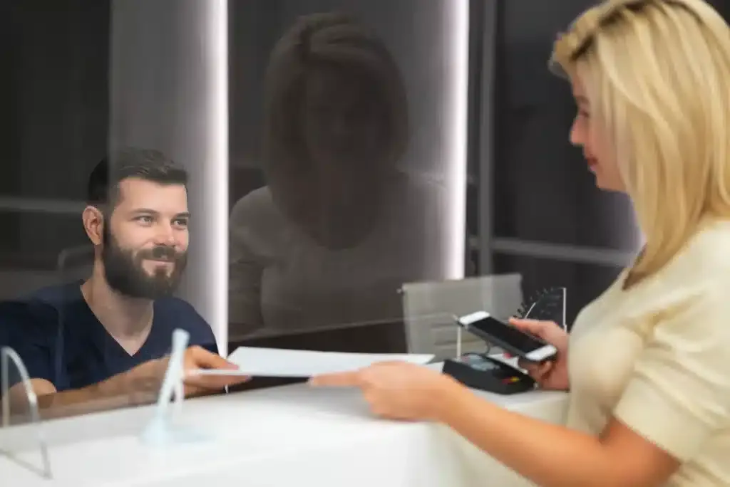 Patient paying dentist office after seeing teeth whitening costs.