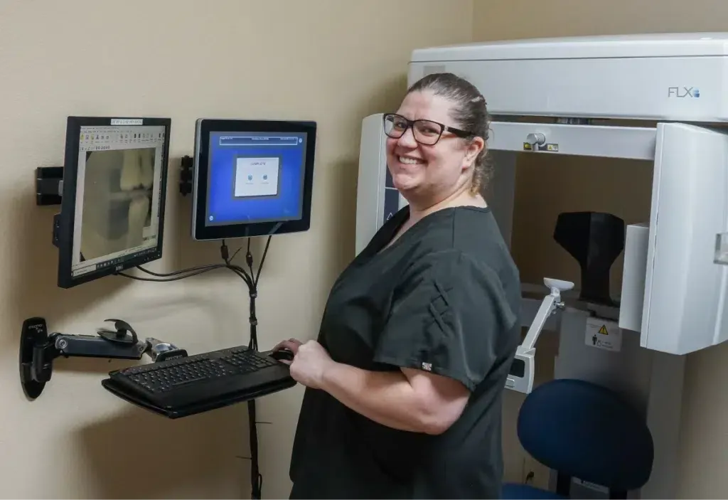 Woman standing next to her computer with x-ray on screen