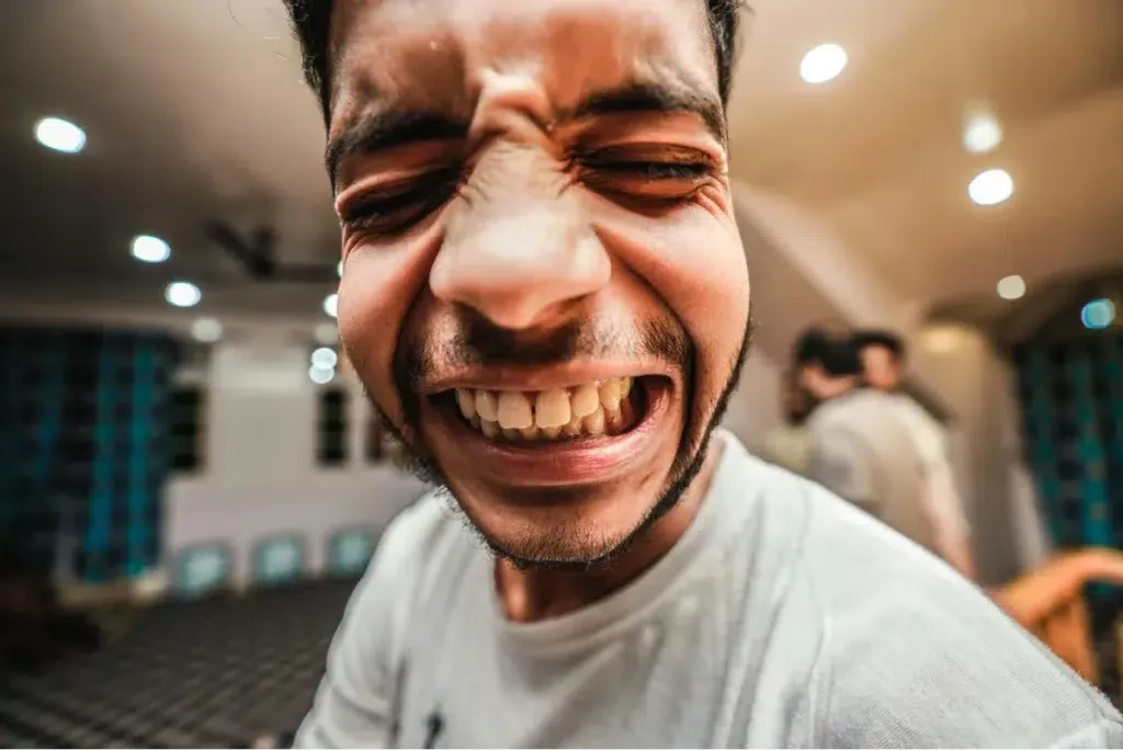 Man with pained expression clenching his teeth