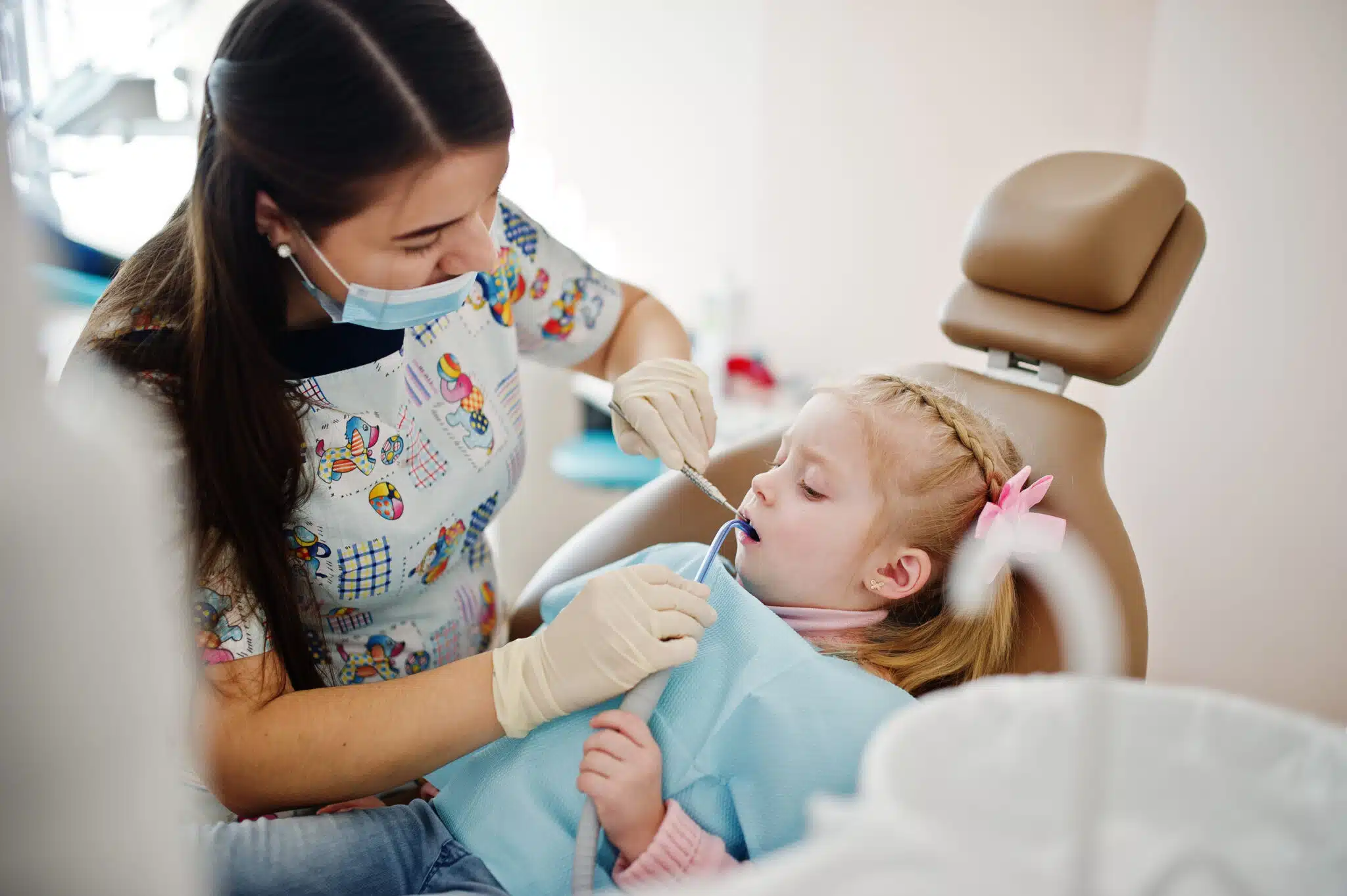 Dental Problems from Nail Biting 1 Dentist in patterned scrubs examining a young girl's teeth in a dental chair