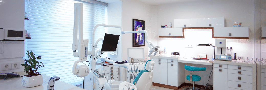 A dental office with a dental chair, cabinets, and a monitor.