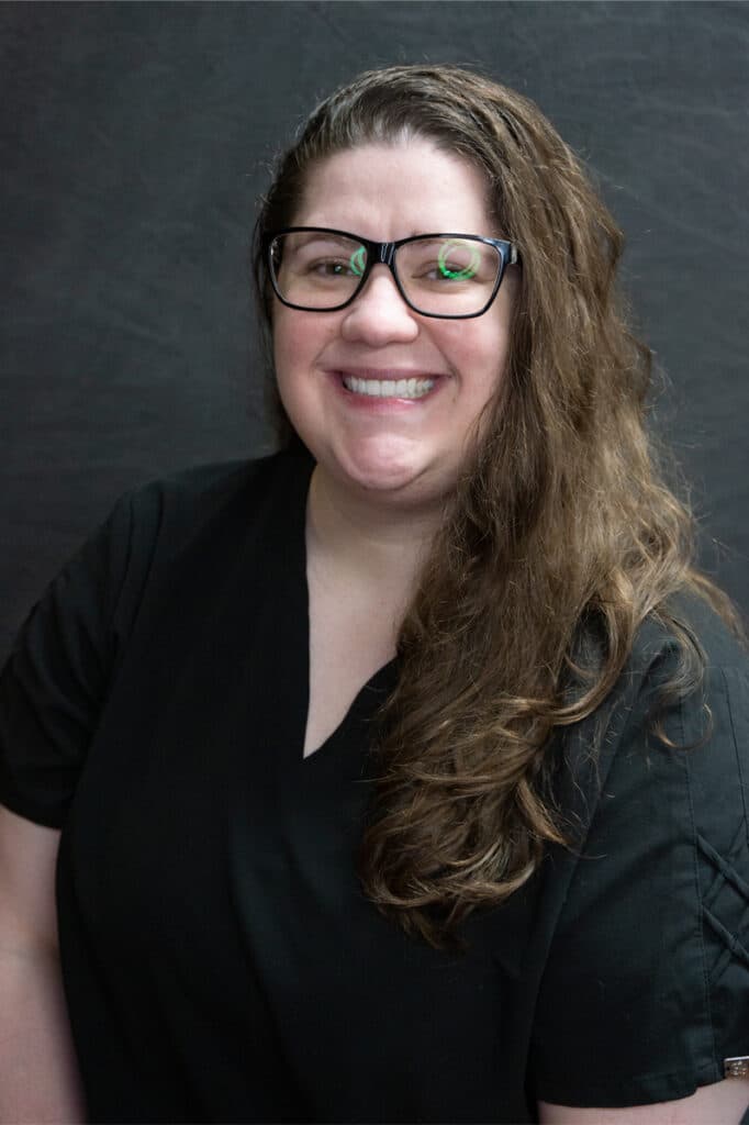 Smiling woman with glasses and long hair.