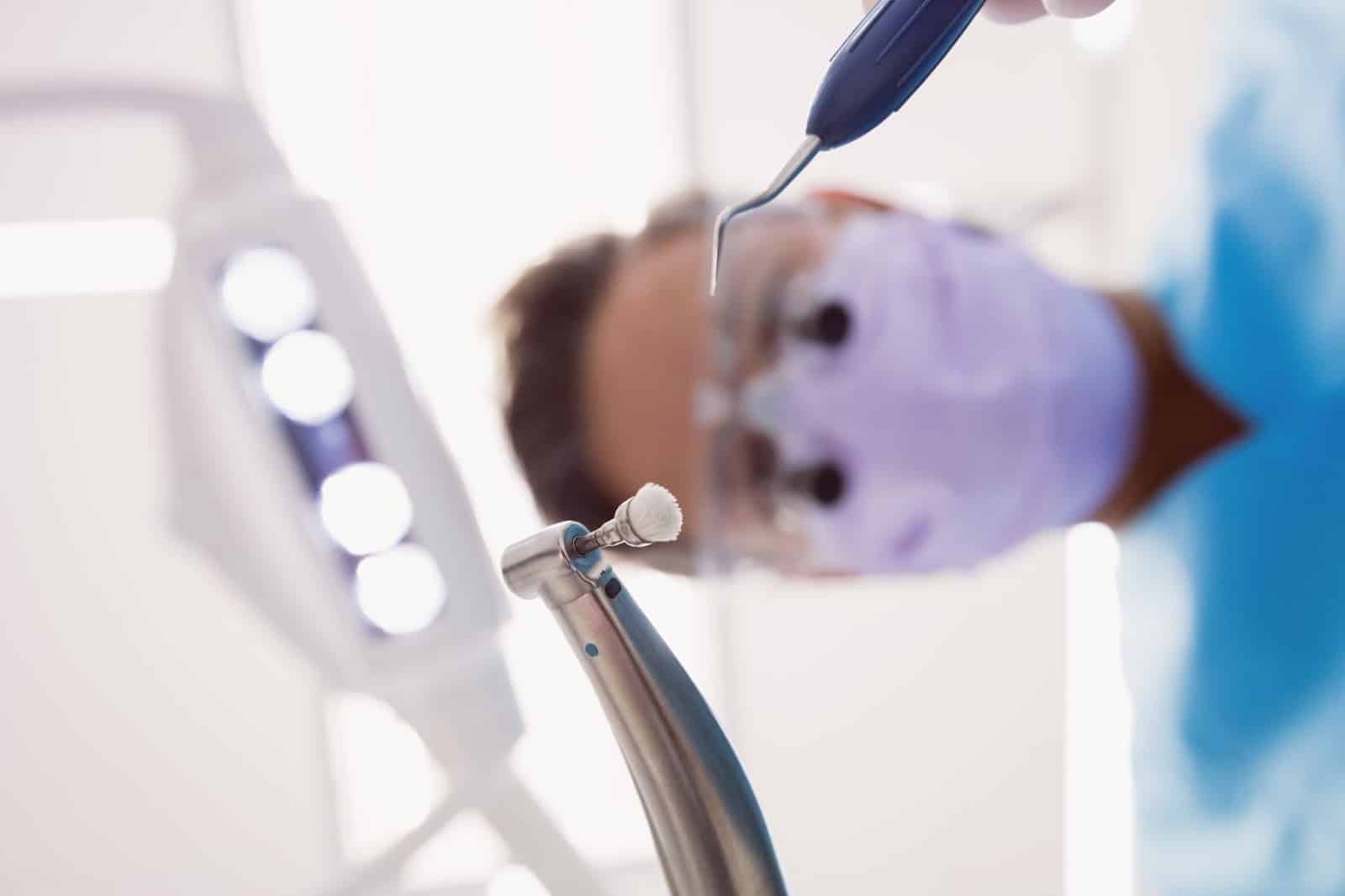 A close up shot of a dentist holding his dental tools.
