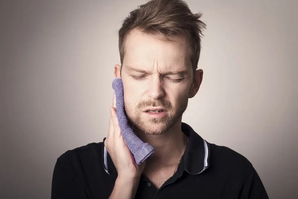 Man holding towel over his jaw and facial muscles