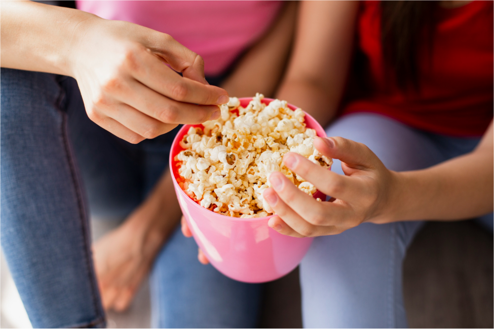 Two people sharing popcorn.