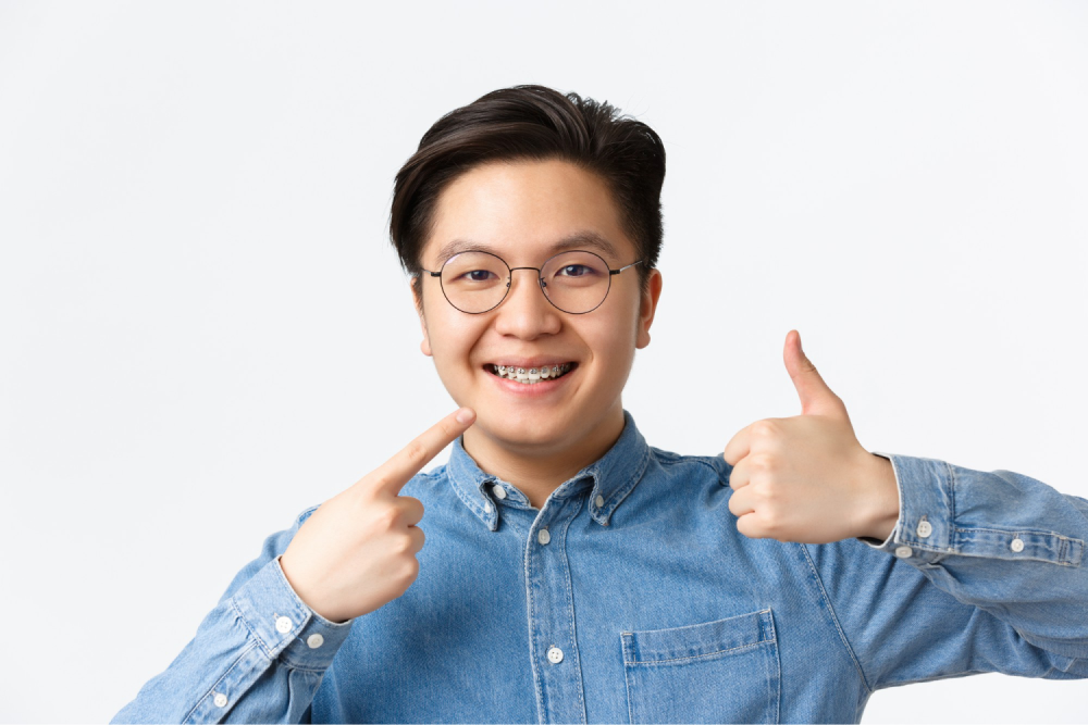 Man smiling with braces and thumbs-up.