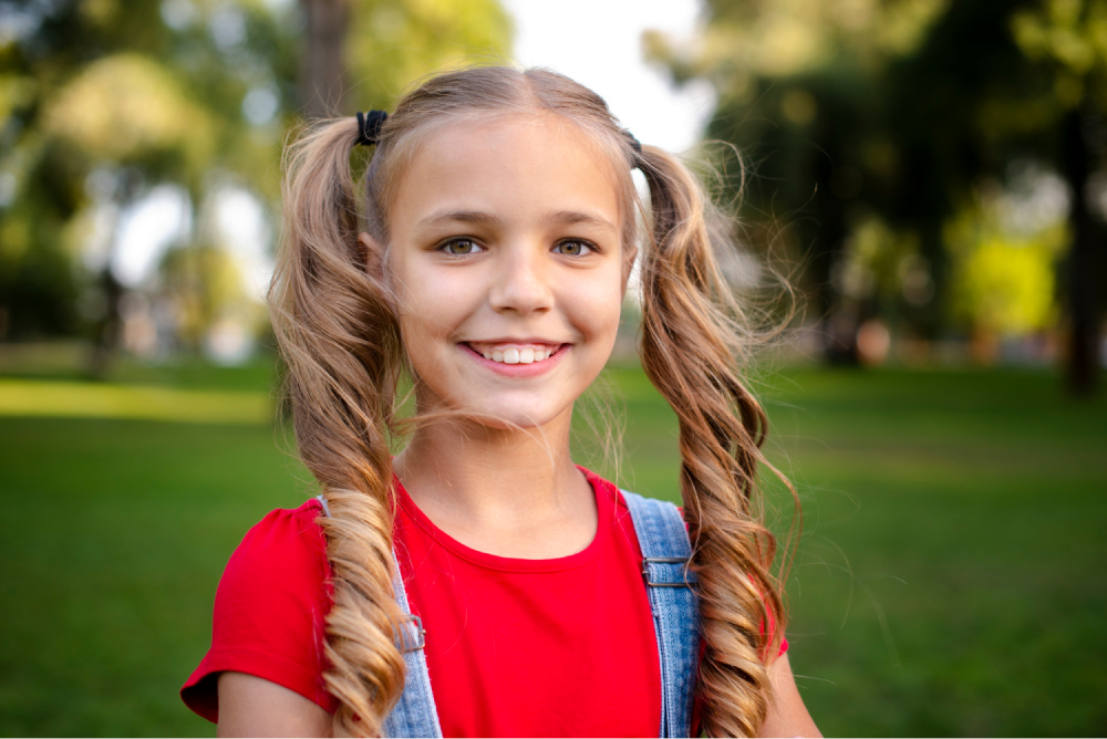 Smiling girl with pigtails outside.