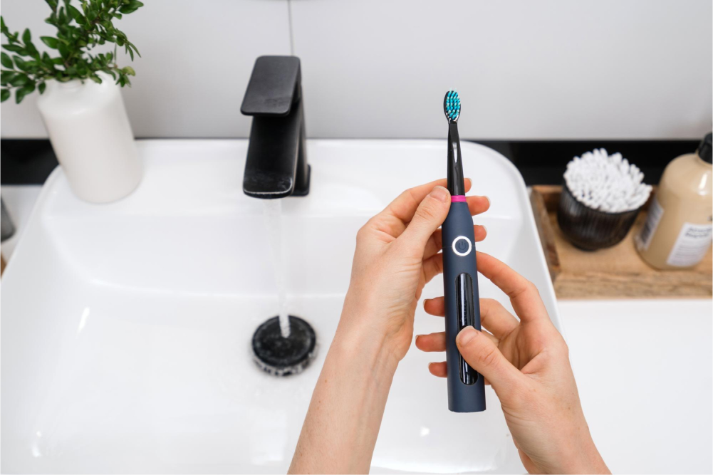 Holding electric toothbrush by sink